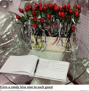 Candy kiss roses in a container on a glass table next to a guest book.