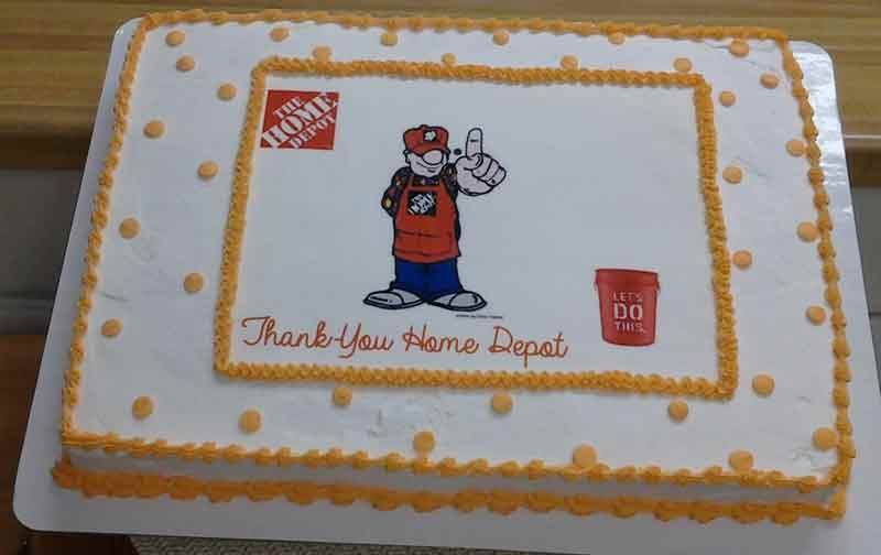 Home Depot-themed cake with logo, cartoon worker, and 
