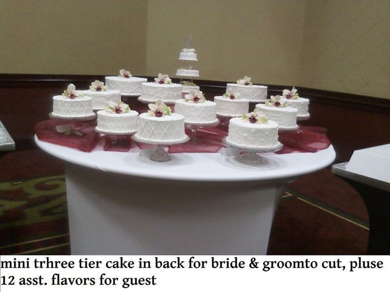 Miniature cakes for guests around a table, with a three-tier cake in the back for the bride and groom.