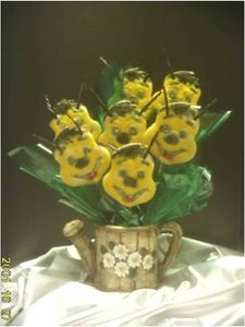 Bee-shaped cookies arranged in a watering can, decorated as a bouquet with green cellophane.
