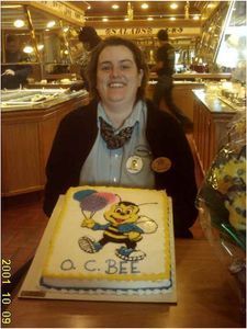Woman smiling, holding cake with cartoon bee and 