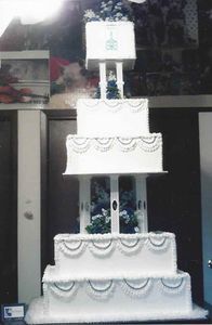 Multi-tiered white wedding cake with intricate piped frosting and decorative structure.