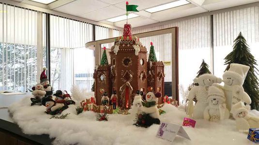 Gingerbread castle Christmas display with snow, snowmen, and Christmas trees.