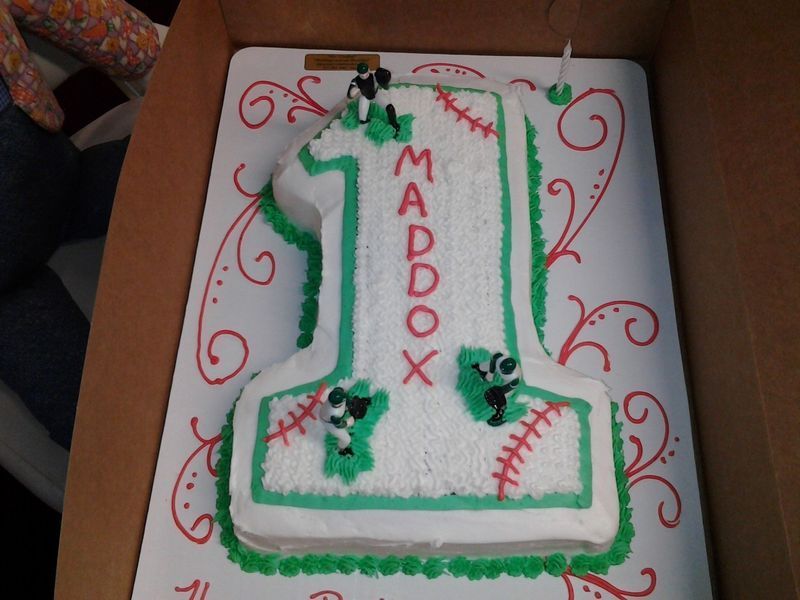 Cake shaped like a number 1, decorated as a baseball. 
