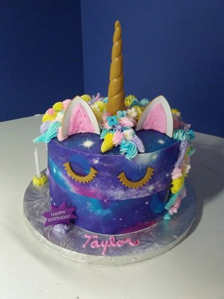 Unicorn cake with galaxy design, gold horn, ears, and closed eyes; 