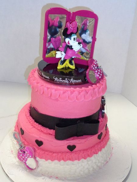 Pink Minnie Mouse themed tiered cake with bow, shoes, and figurine.