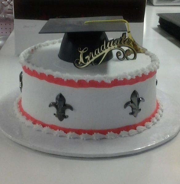 Graduation cake with white frosting, red trim, black mortarboard, gold 