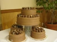 Chocolate cake tower with three tiers and three small cakes, all decorated with chocolate frosting and candies.