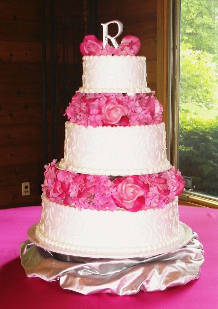 Five-tiered white cake with pink floral accents, 