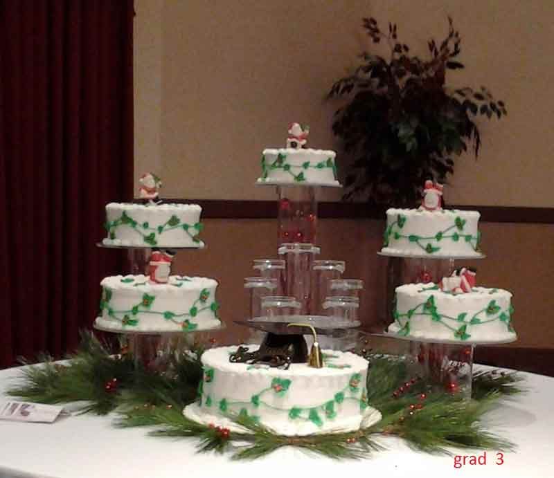 Christmas cakes on tiered stands, decorated with garland and Santa figures, on a table.