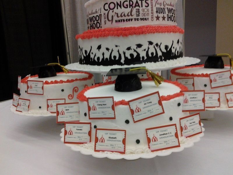 Graduation cake tiers with red and white frosting, topped with grad caps and name cards.
