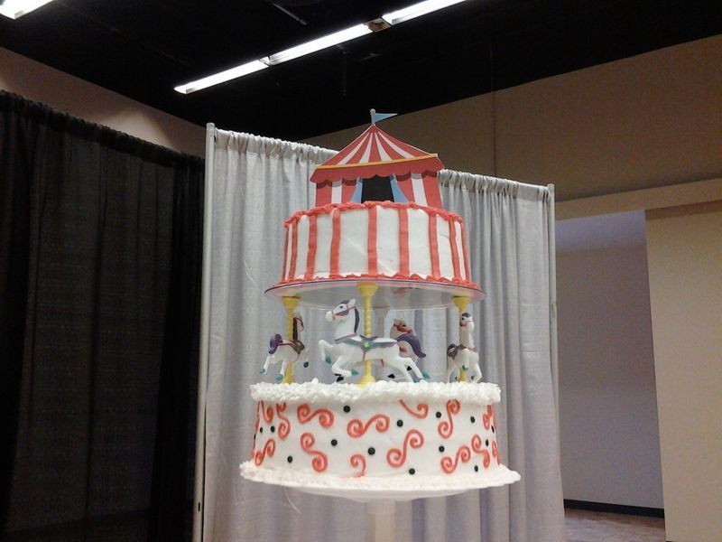 Cake decorated as a carousel, three tiers, red and white, with horses.