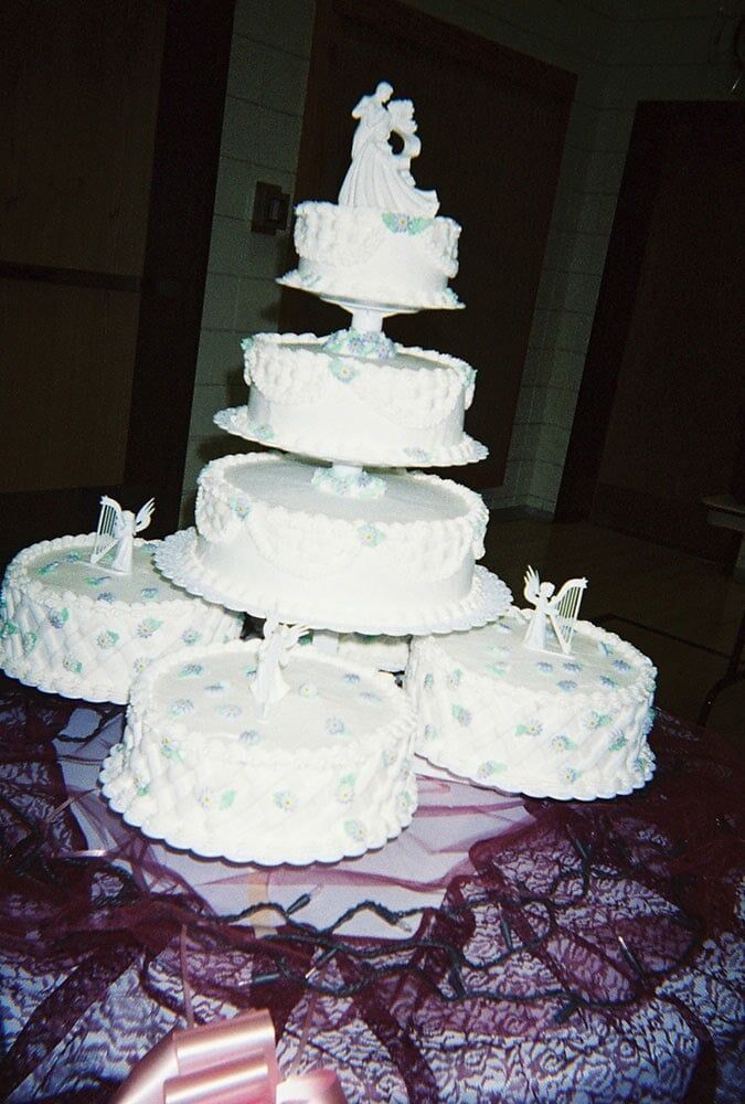 Wedding cake with tiers of white frosting and bride/groom topper.