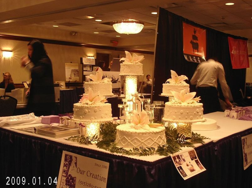 Wedding cakes display at a venue, with guests and vendors present.