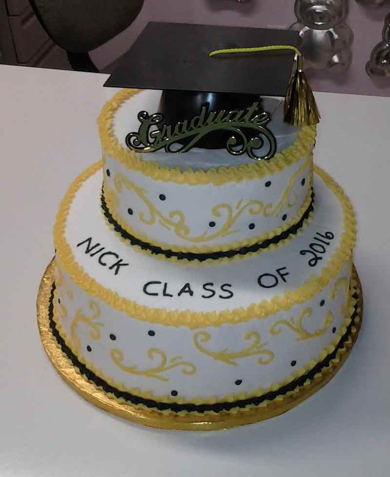 Two-tier graduation cake decorated in yellow and black, with a mortarboard on top. Text reads 