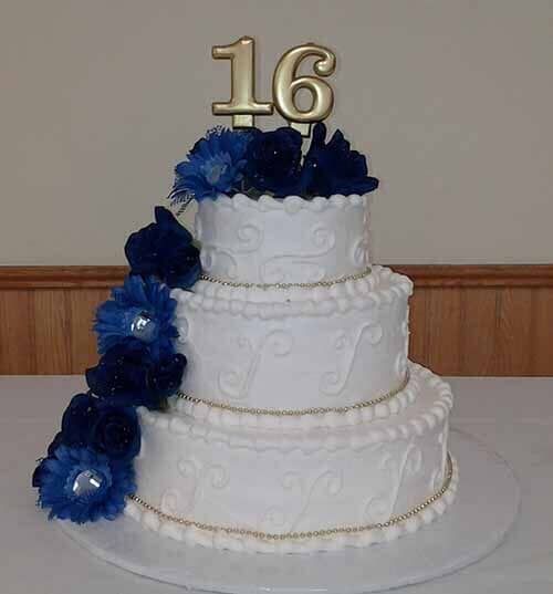 Three-tiered white cake with blue flower cascade, gold 