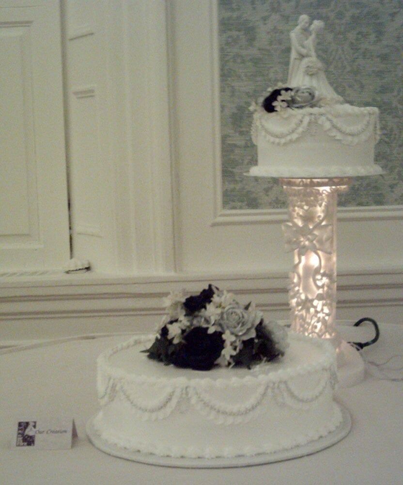 Wedding cake with two tiers, flowers, and a bride and groom topper.