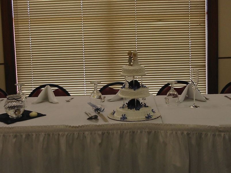 Wedding cake centerpiece on a decorated table in front of a window with blinds.