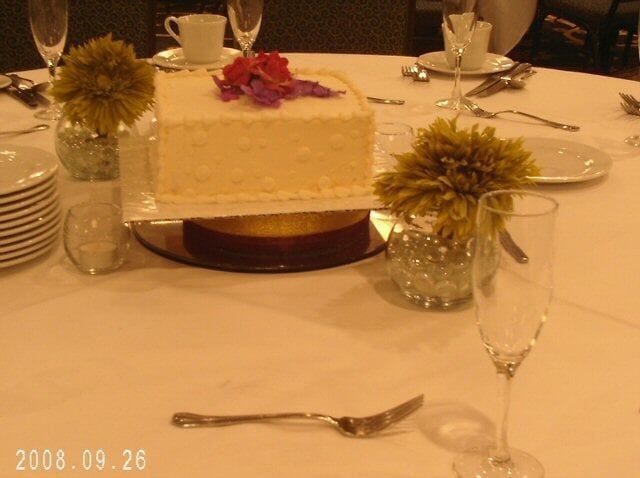 Wedding cake on a table set for guests, with flowers and champagne flutes.