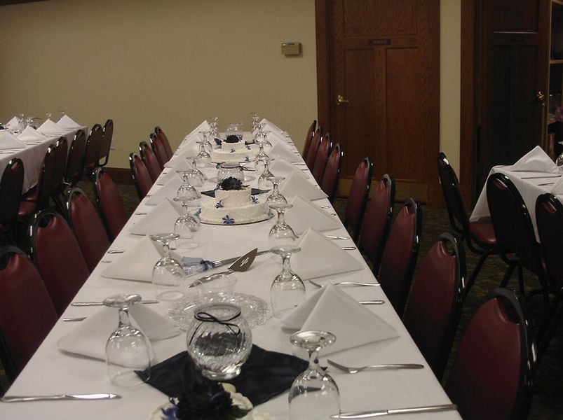 Long banquet table set for a formal event with white tablecloth, glasses, and napkins.