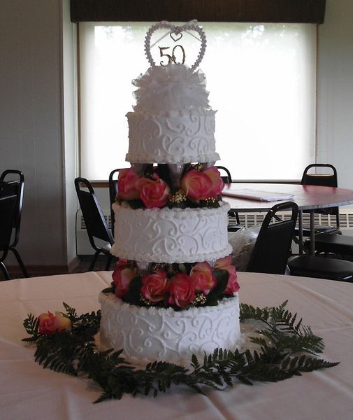 Four-tier white cake decorated with pink roses and 