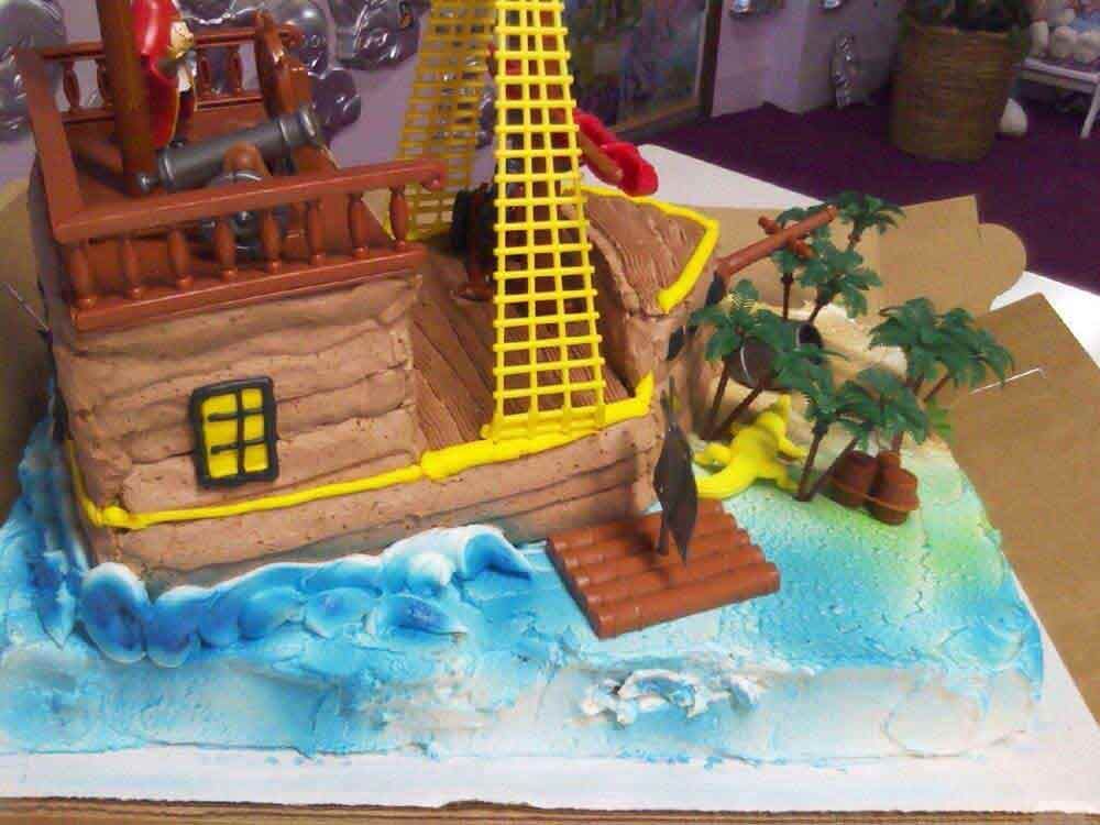 Pirate ship cake with brown frosting, edible waves, palm trees, and a cannon.