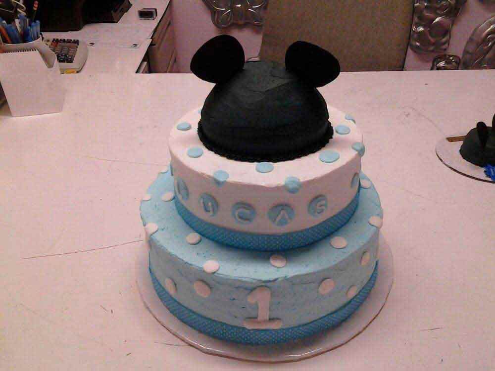 Two-tiered cake decorated as Mickey Mouse. Blue and white frosting with a black hat on top, 