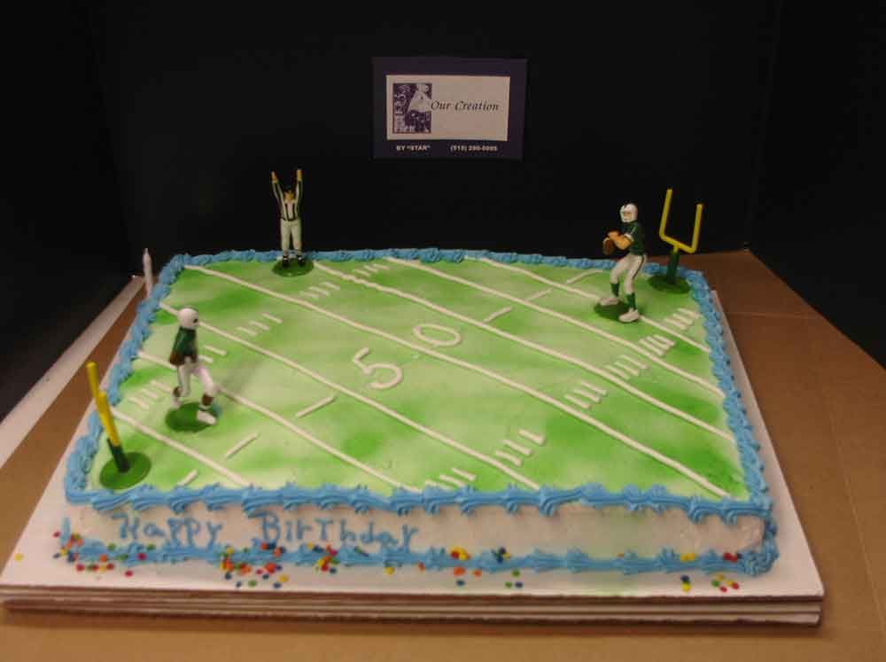 Football-themed birthday cake with green field, white yard lines, blue frosting, and football player figurines.