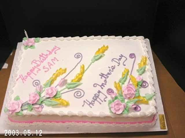 Cake decorated for Mother's Day and a birthday, with frosting flowers and writing on white frosting.