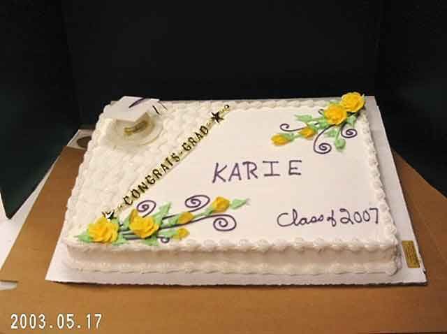 Graduation cake with white frosting, decorated with yellow roses, swirls, and the name 