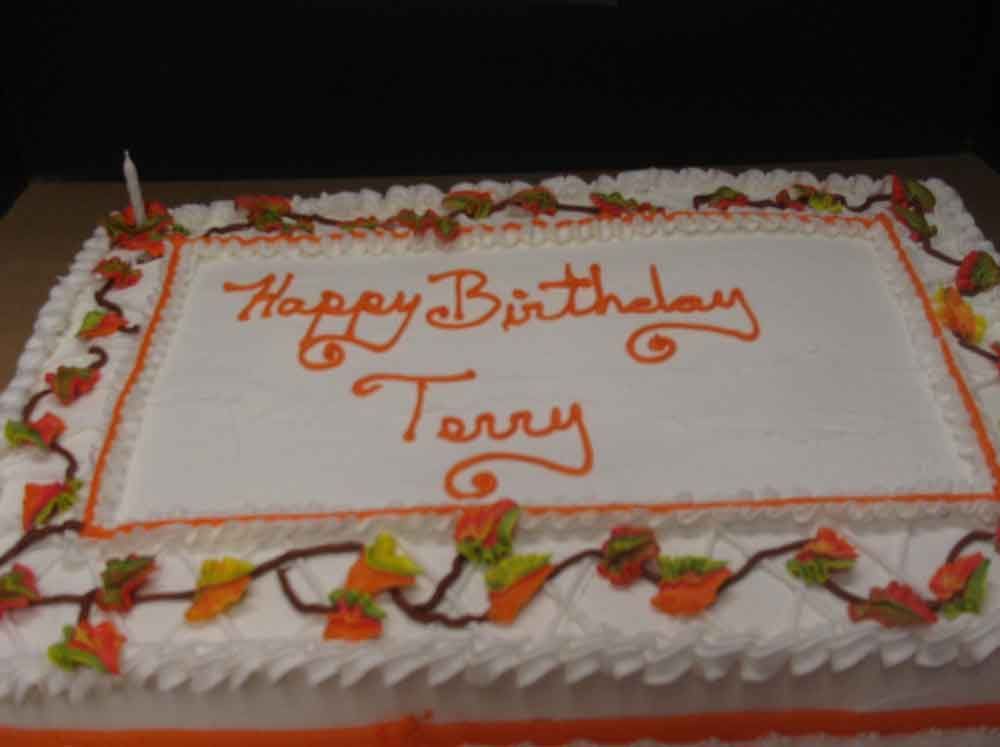 Rectangular birthday cake with white frosting, orange lettering 