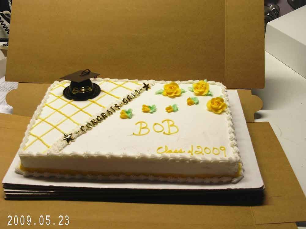 Graduation cake with yellow and white frosting, decorated with a graduation cap and flowers. 