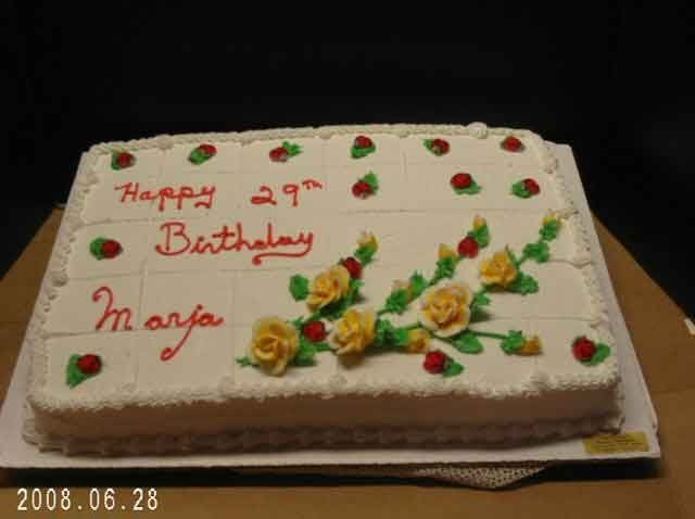 Cake decorated with frosting, Happy 29th Birthday Marja. Yellow roses and red berries.