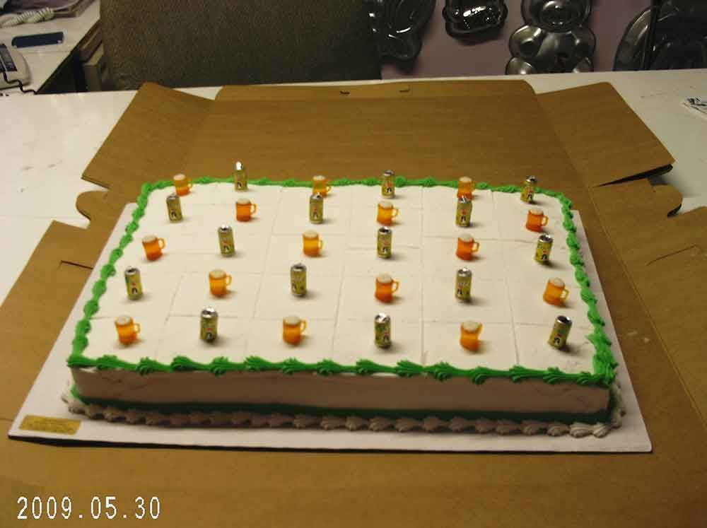 Cake decorated with beer mug candles, on a cardboard box, green and white frosting.