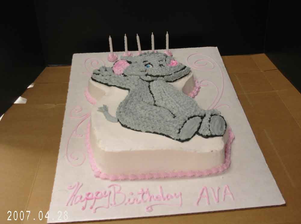 Elephant-shaped birthday cake with pink frosting, four candles, and 