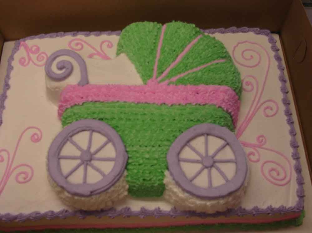 Cake decorated with a stroller design in green, pink, and purple frosting, on a white rectangular cake.
