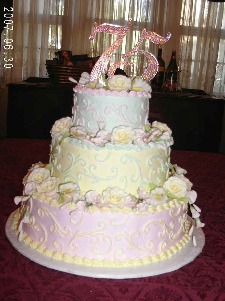 Three-tiered pastel cake with floral decorations, topped with a 