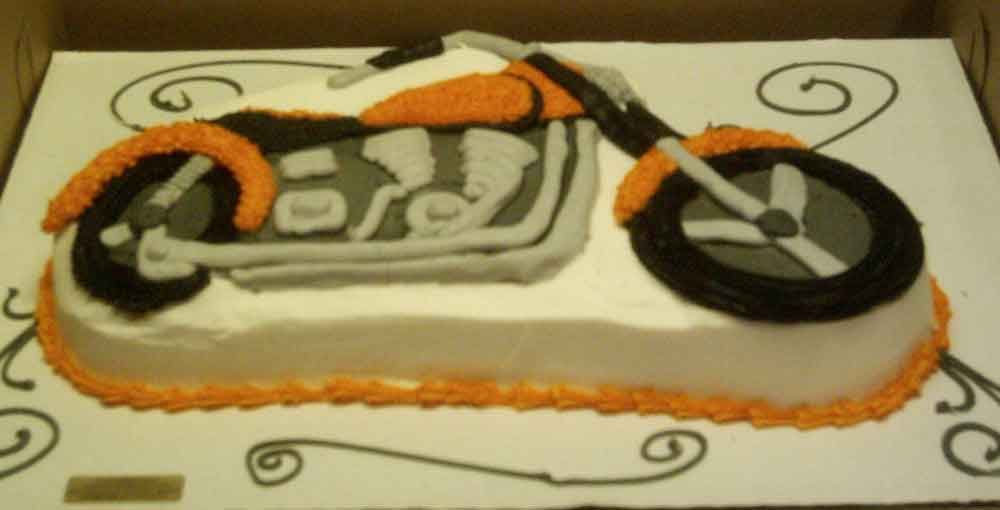 Motorcycle-shaped cake with orange and black accents.