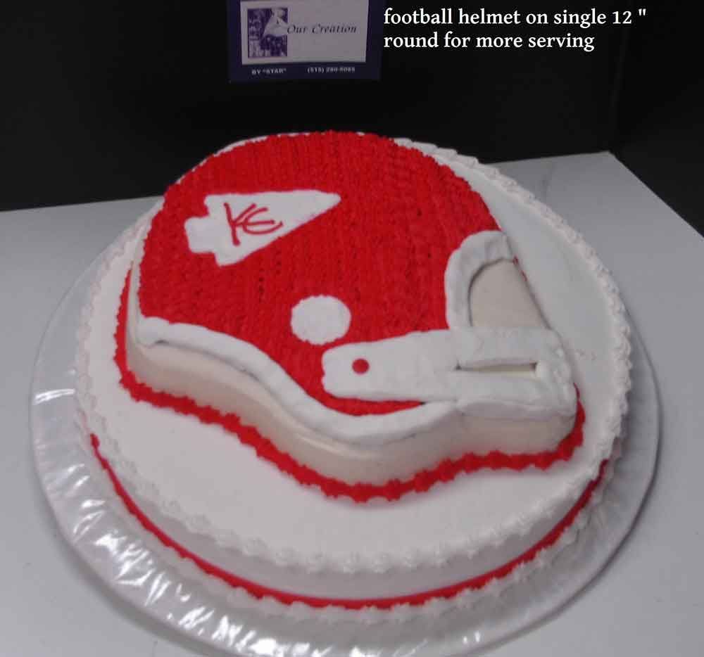 Football helmet cake with red frosting, KC logo, on a white cake base.