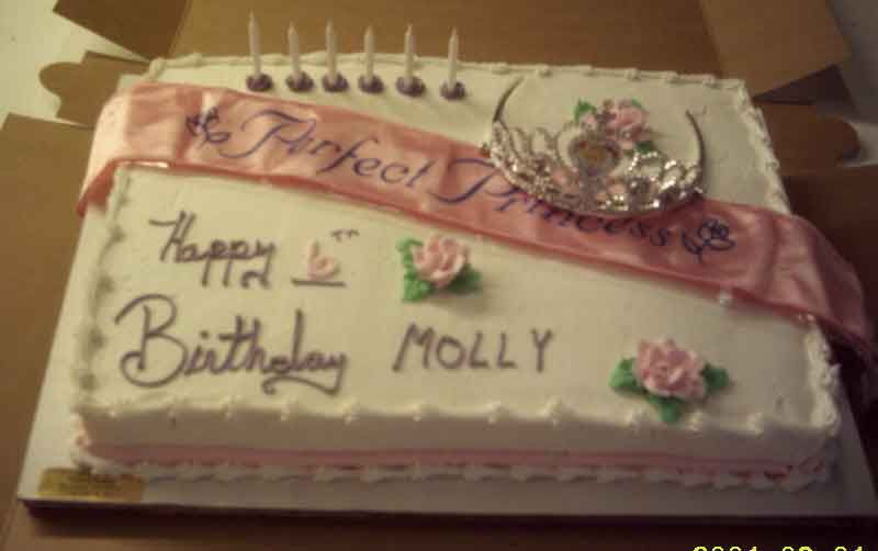 Cake decorated for Molly's birthday. White frosting with pink accents, a sash that reads 