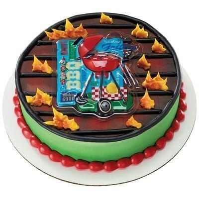 Cake decorated as a barbecue grill, with flames and a grill-shaped topper, on a white plate.