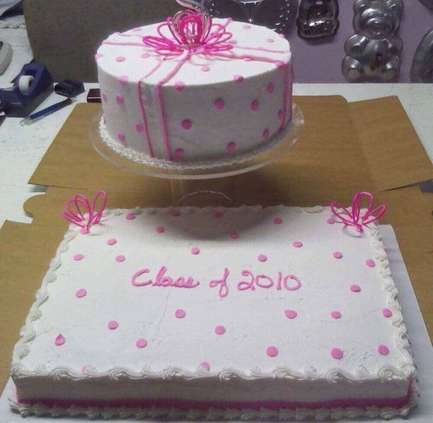 Two graduation cakes, round and rectangular, decorated in white frosting with pink polka dots and 