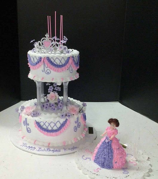 Two-tiered birthday cake with princess figurine. Pink and purple frosting, tiara, candles. 