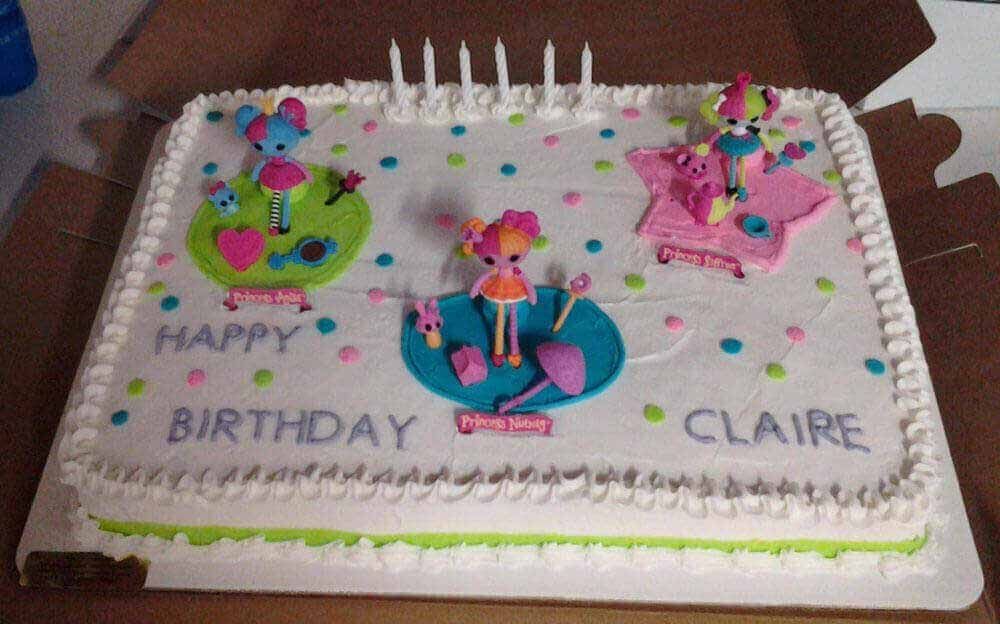 Birthday cake decorated with three Lalaloopsy figures, candles, and the name 