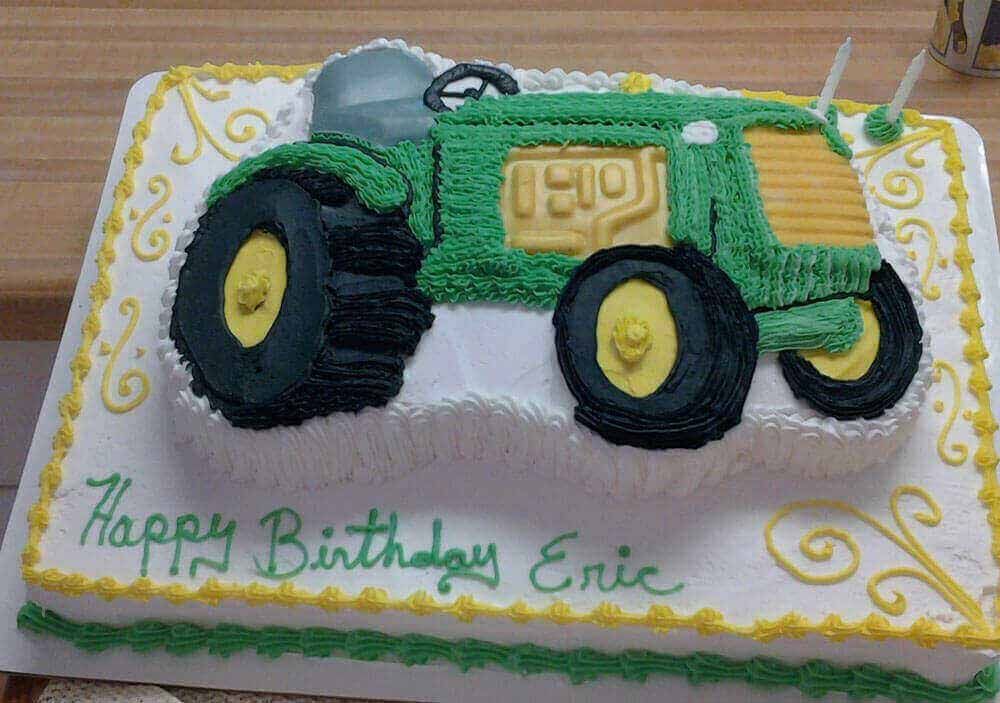 Green tractor-shaped birthday cake with yellow and white frosting, saying 