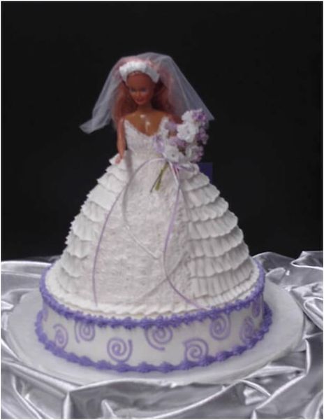 Wedding cake with doll bride, white and purple frosting, on a white platter.