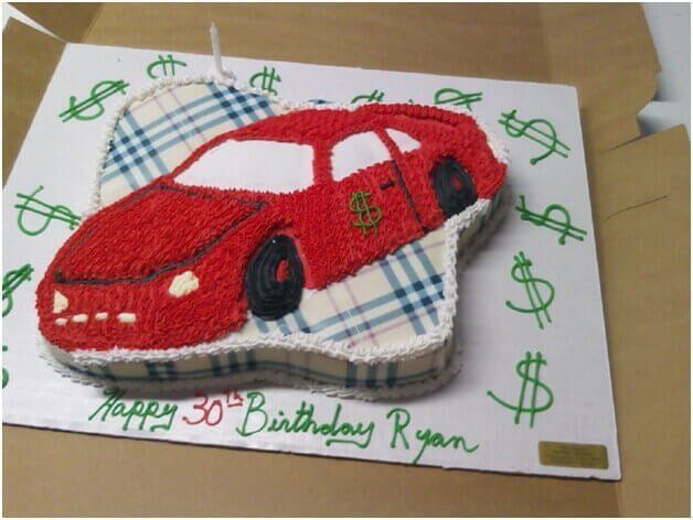 Red car-shaped birthday cake on plaid pattern, green dollar signs, 