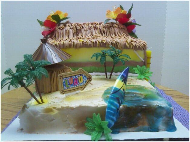 Tropical-themed cake: a thatch-roofed hut, beach scene with a surfboard and palm trees.