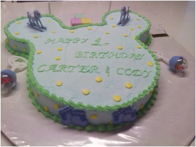 Blue Mickey Mouse-shaped birthday cake with green frosting, yellow dots, and 