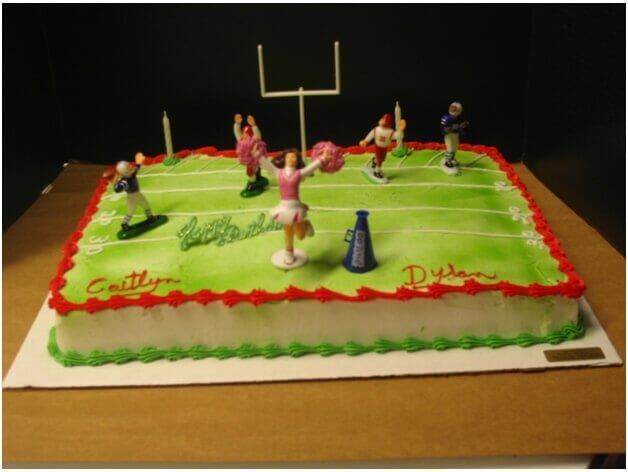 Football-themed birthday cake with green field, red trim, football players, cheerleaders, and goalpost.